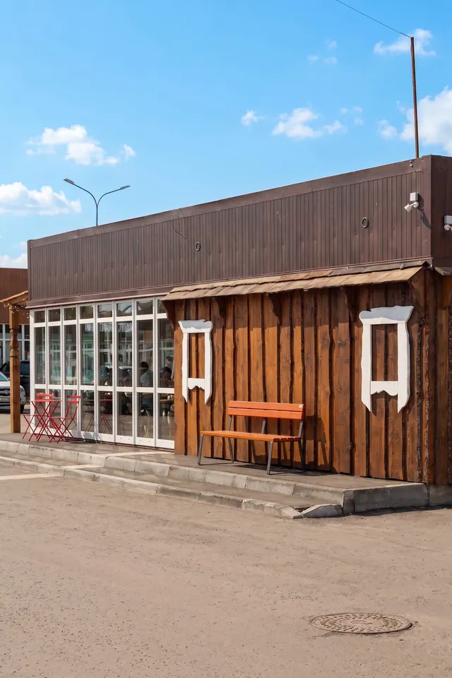 Белый резной наличник на тёмной дощатой стене магазина